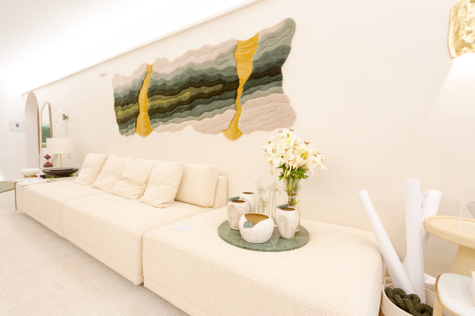 Close view of the white sofa, flowers and green wall hanging in the CASACOR lounge