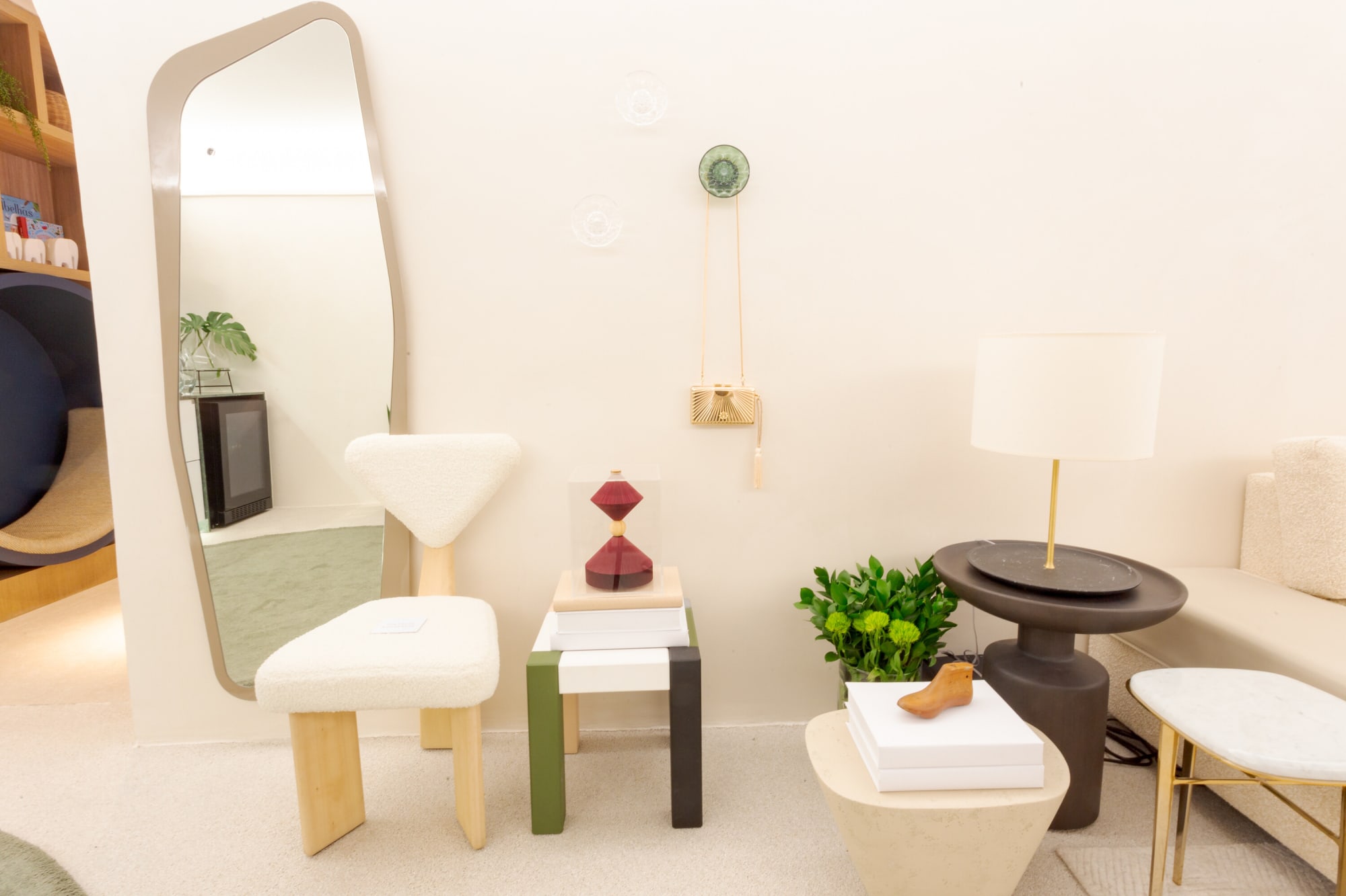 White sculpted chair, mirror and lamp beside small side tables in a white corner