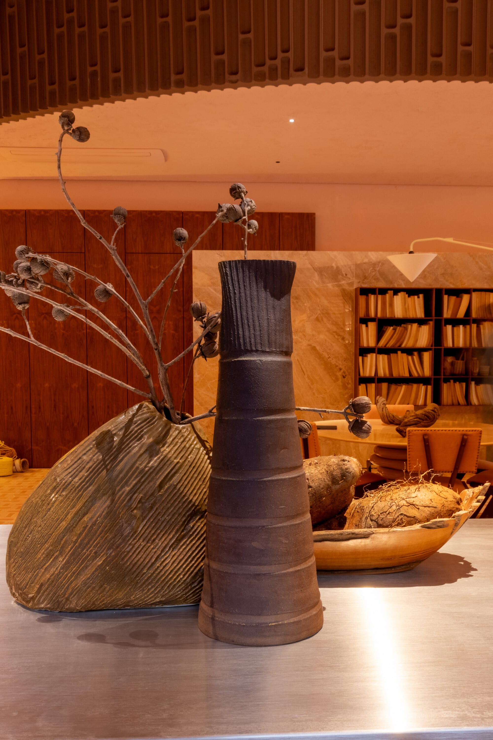 Carved timber leaf sculpture and a ceramic vase on a steel counter