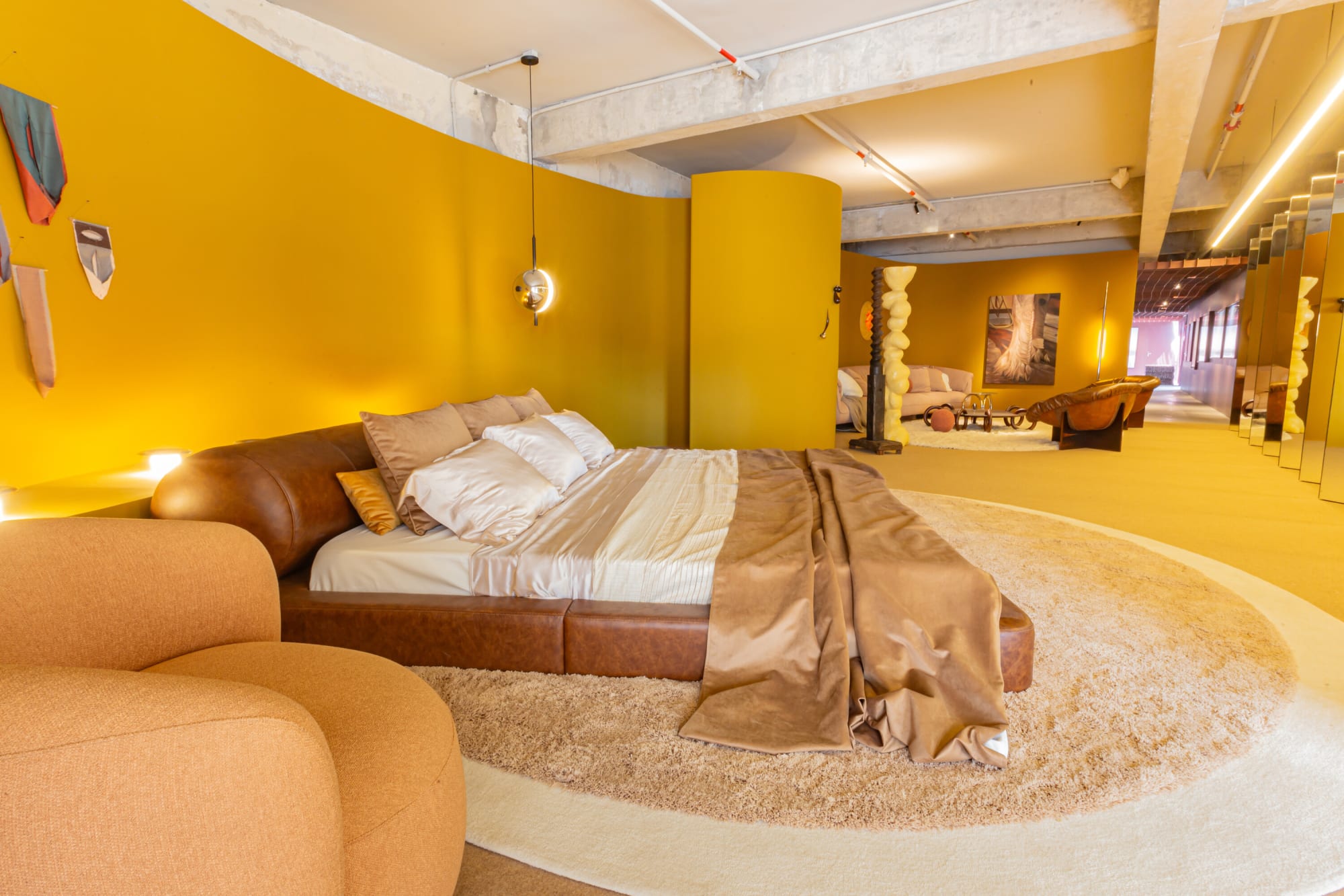 Leather bed with satin throw and a peach armchair on a shaggy rug in the saffron suite