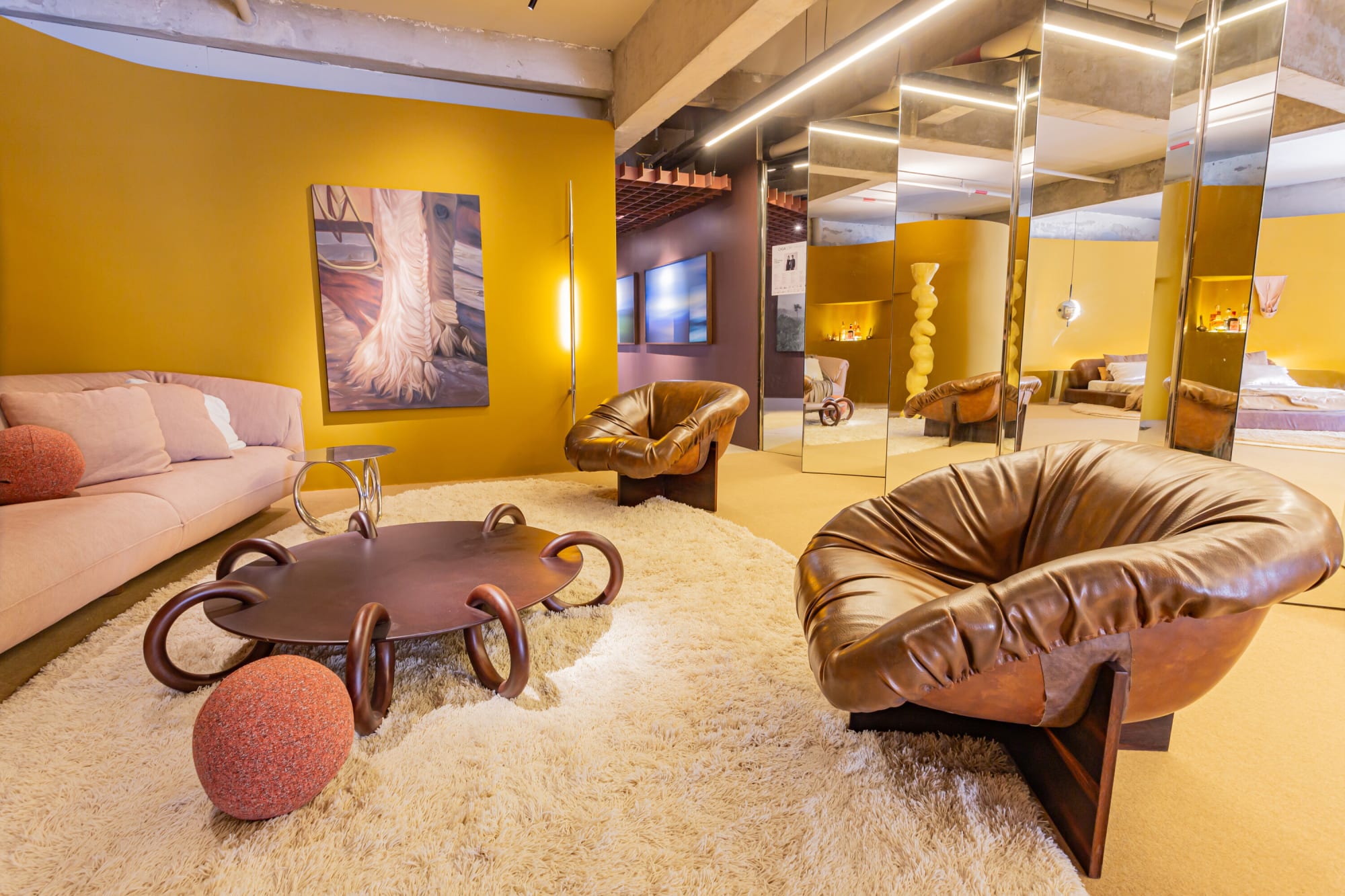 Leather lounge chair, ring legged table and pink sofa on a shaggy rug before saffron walls