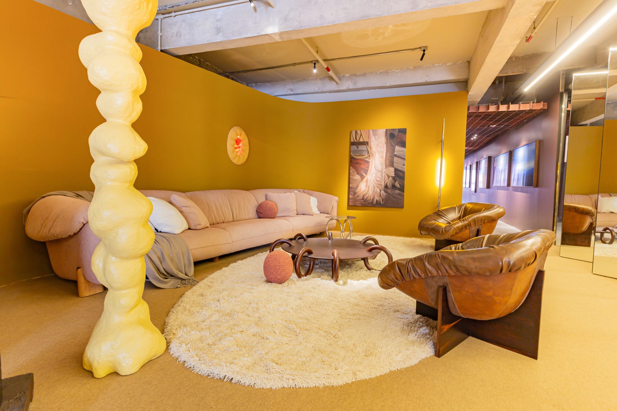 Pale yellow sculpted column before a pink sofa and leather chair in the saffron suite