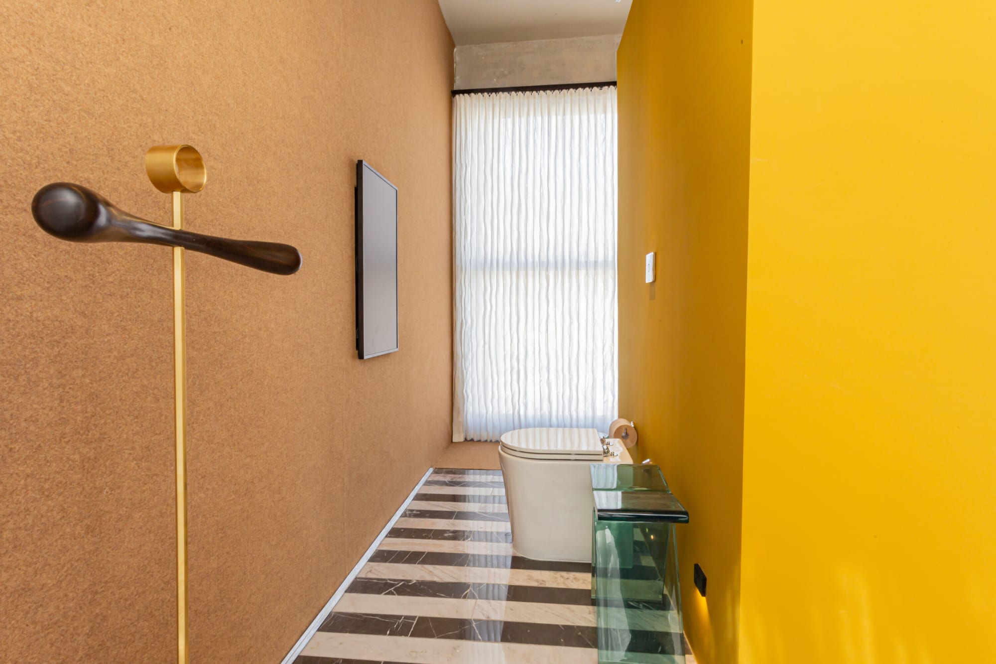 Brown corridor with a sculptural wall hook leading to a striped marble bathroom