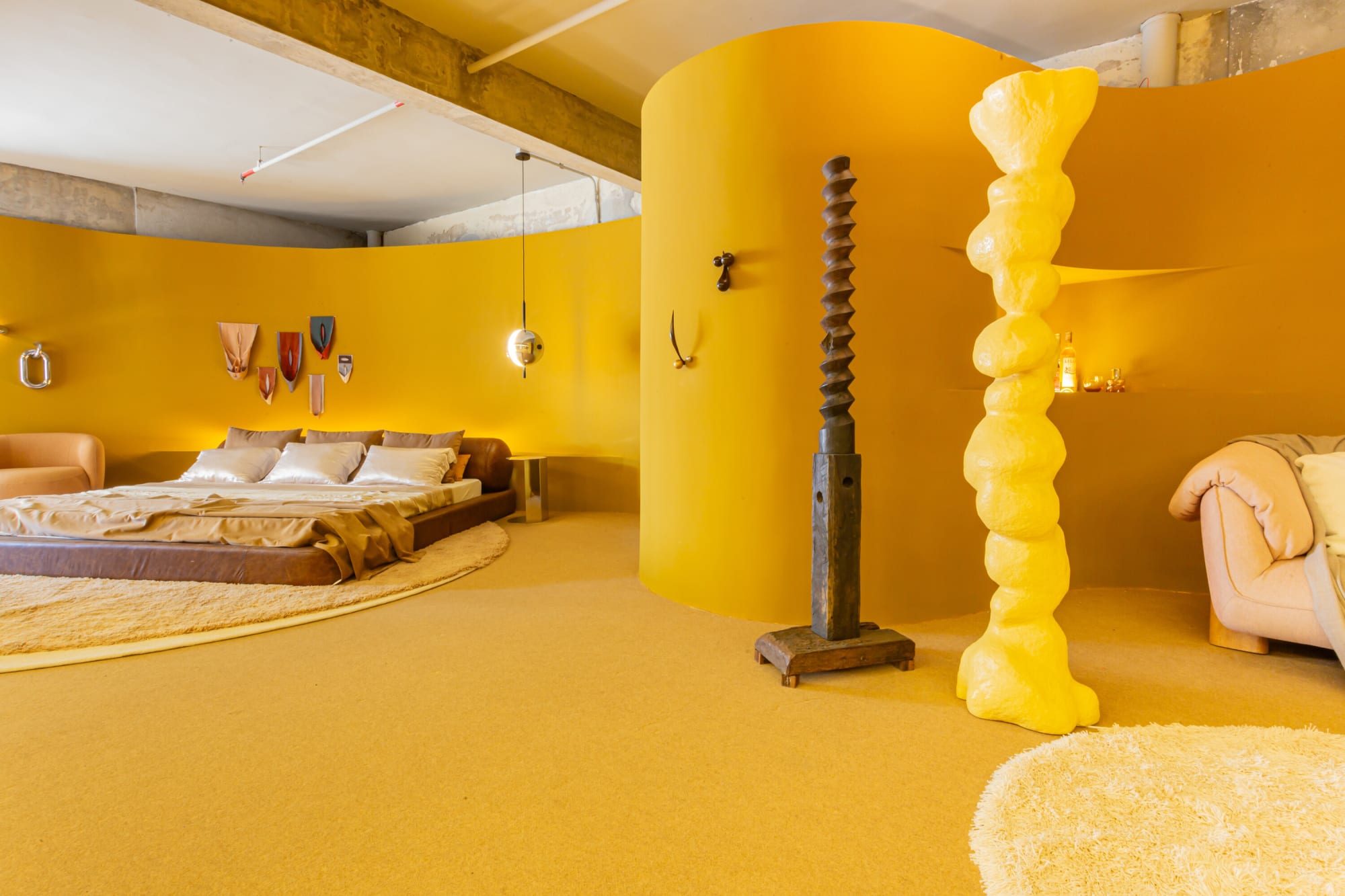 Curved saffron wall with yellow sculpted column and a carved timber totem