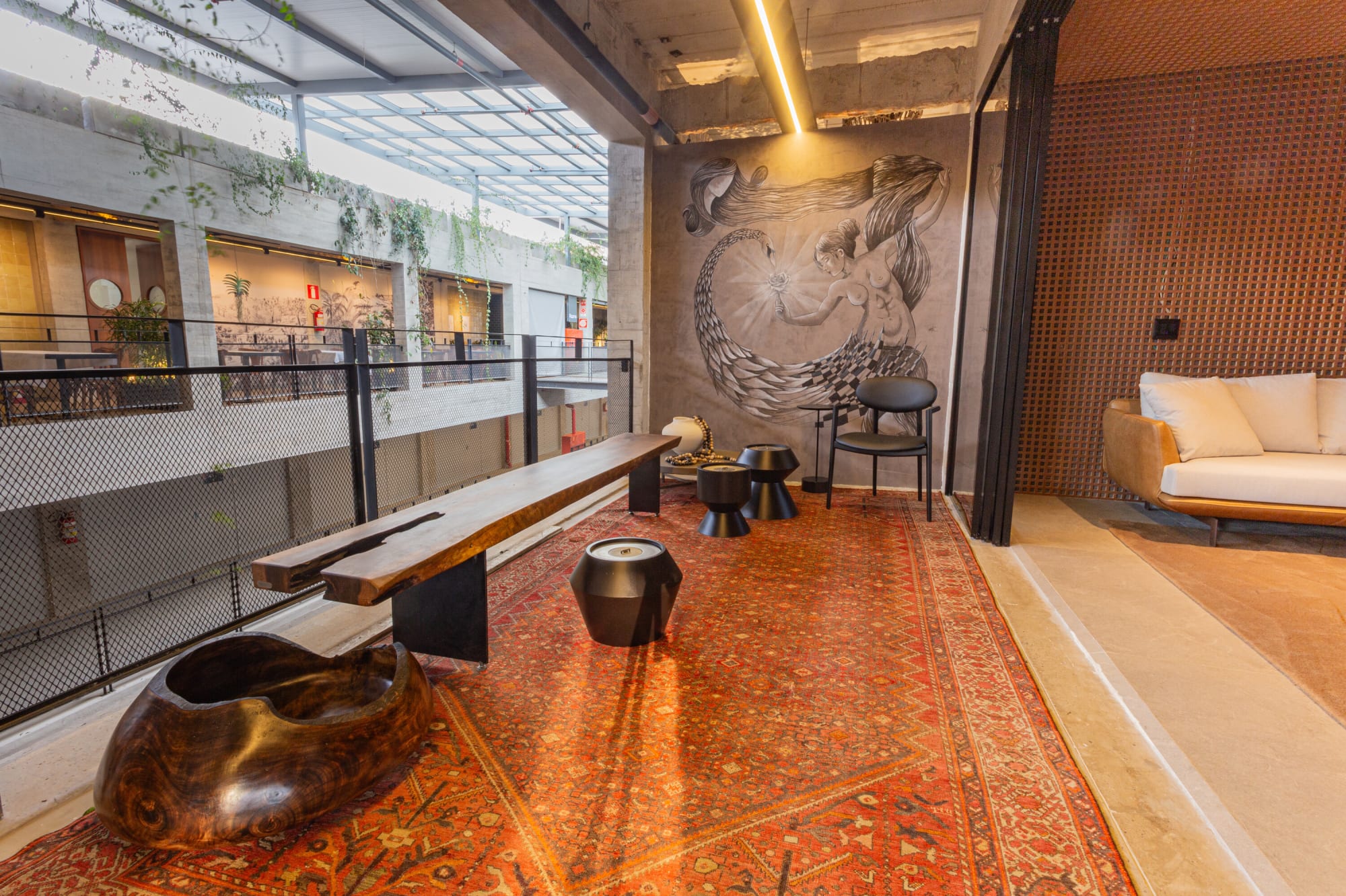 CASACORのアトリウムを見下ろすバルコニーの木のベンチと赤いペルシャ絨毯