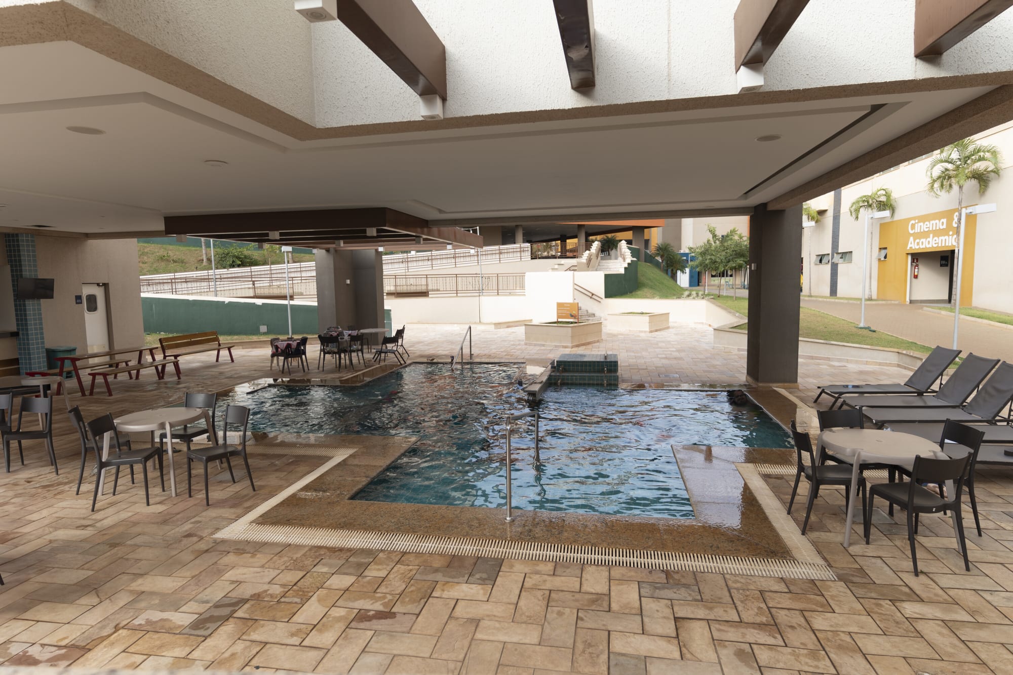 Covered indoor pool with grey dining tables and timber ceiling beams