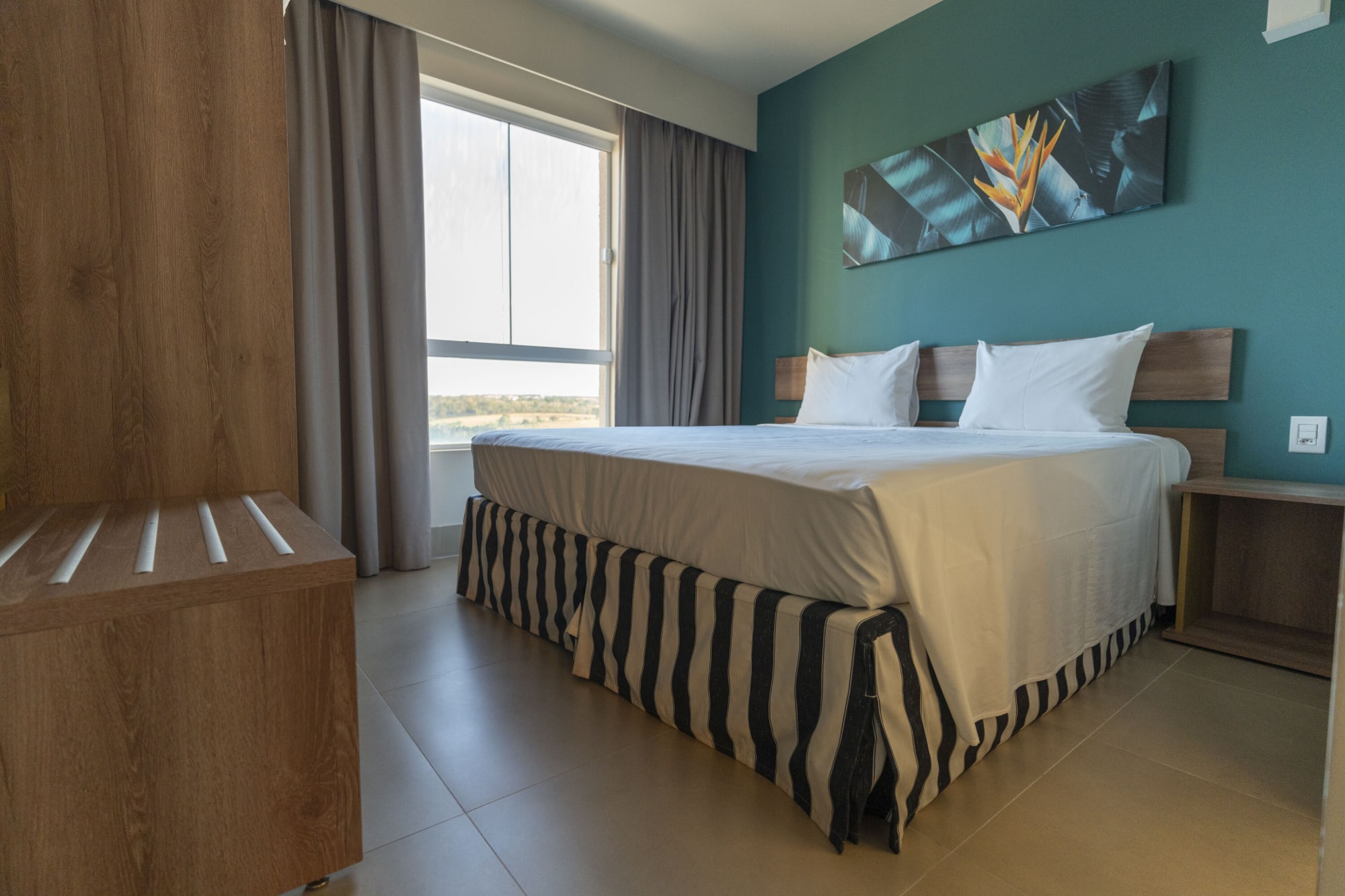 Resort room with striped bed skirt, teal wall and window light