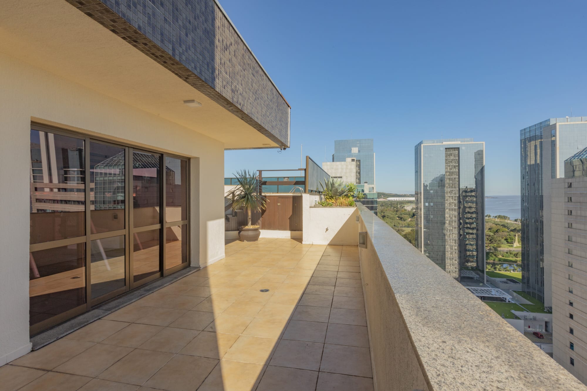 Long tiled balcony along the hotel facade beside glass office towers