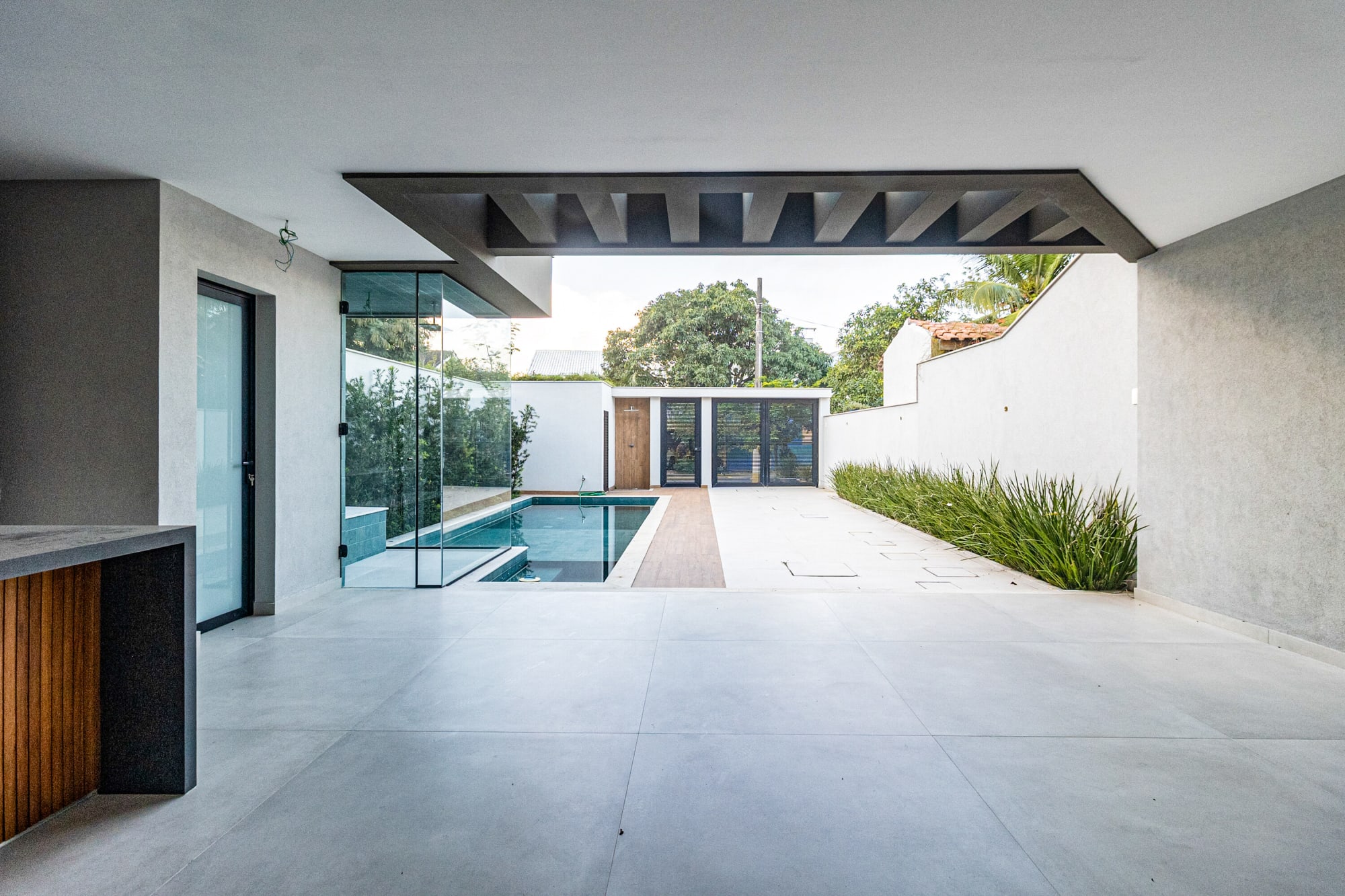 Covered porch of grey porcelain tiles looking along the lap pool to the gate