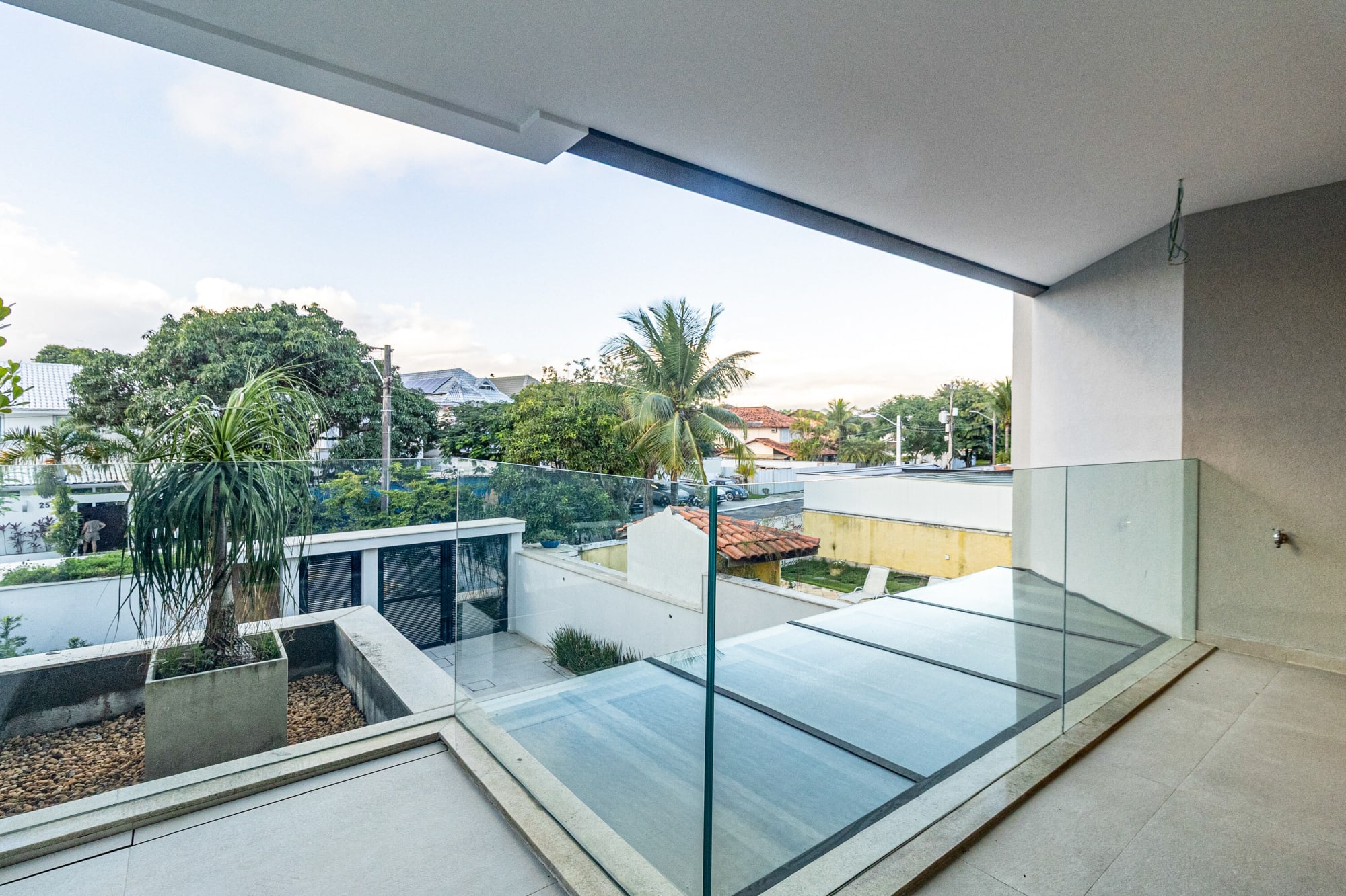 Upper balcony with glass balustrade over the pool deck and neighbourhood palms