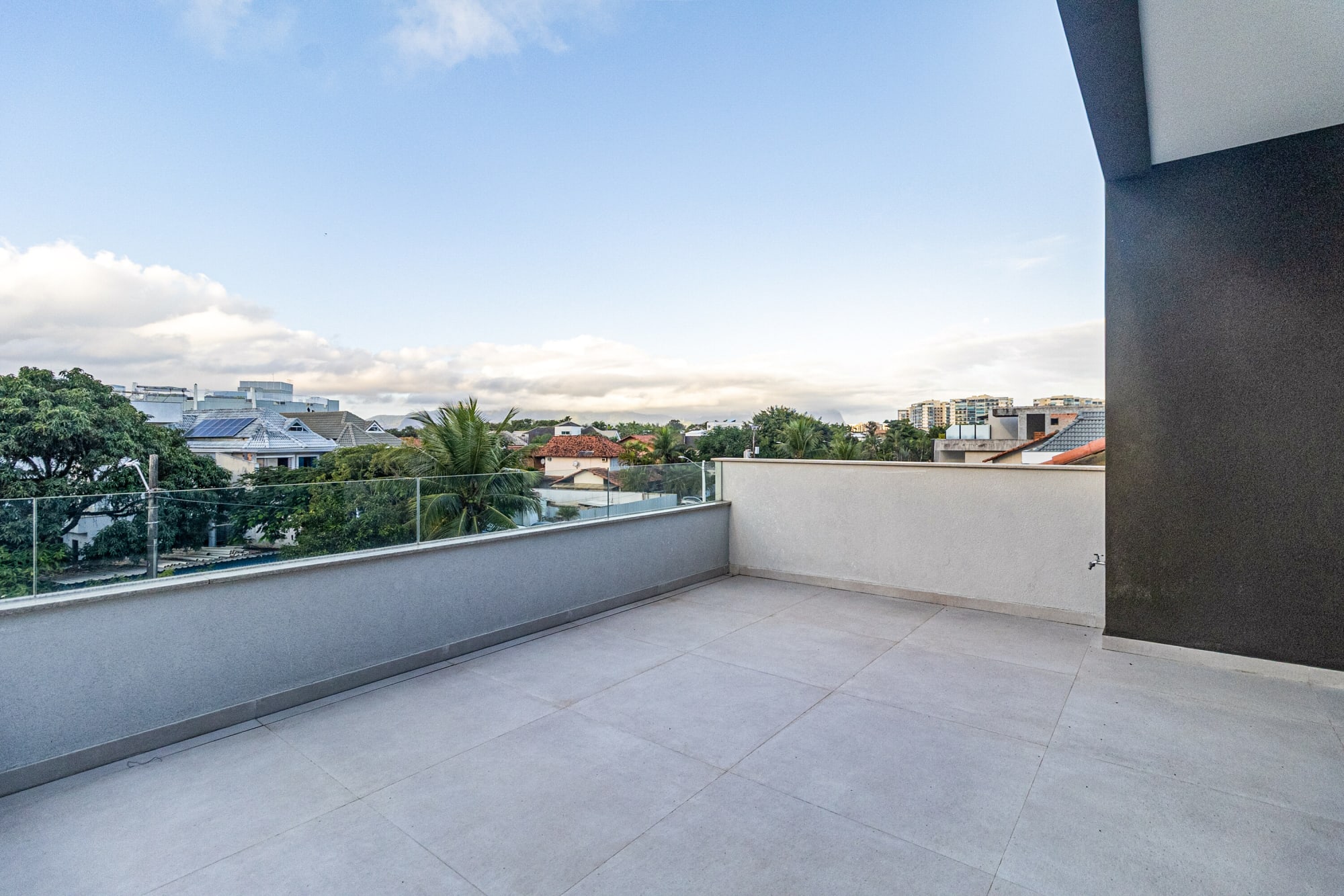 Empty roof terrace with low wall and skyline of Barra houses at dusk