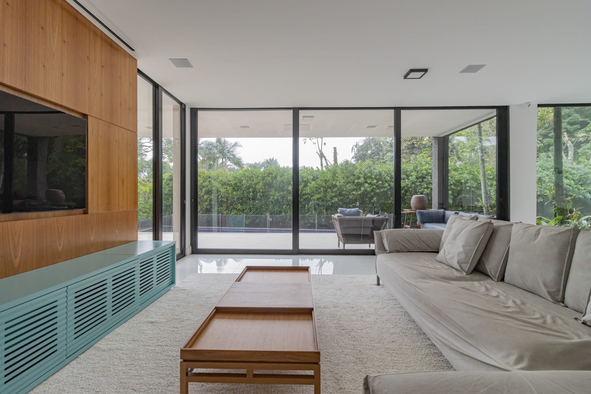 Living room with timber coffee table, grey sofa and teal sideboard by the glass