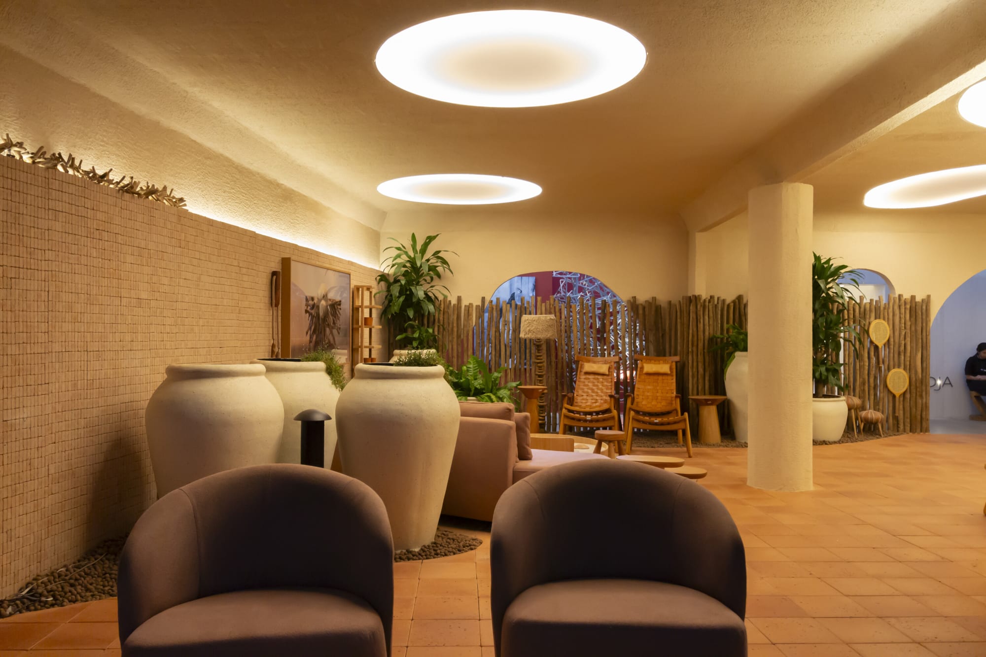 Two plum tub chairs facing large cream urns and pole screens in the resort lounge