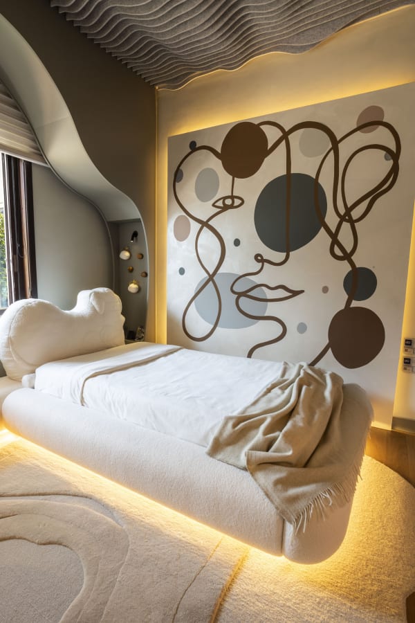 Line drawn face mural above a floating bed under a pleated fabric ceiling