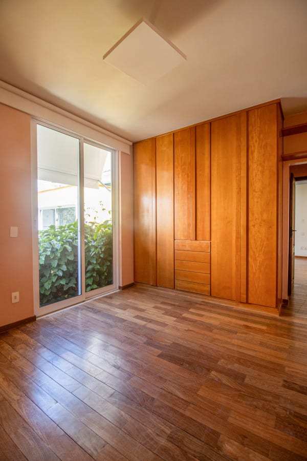 Orange bedroom with timber wardrobe and parquet floor by a glass door