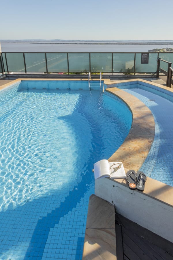 Curved rooftop pool with towel and flip flops on the ledge over the river