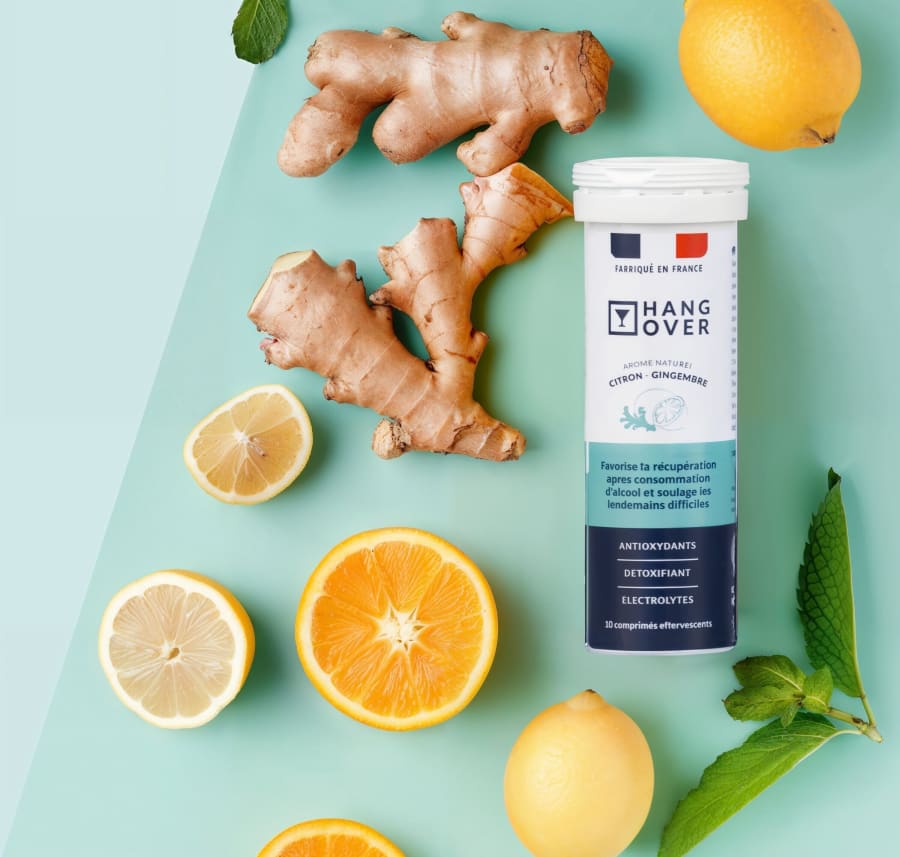 Hangover lemon ginger tube with ginger root, halved lemons and orange on mint blue