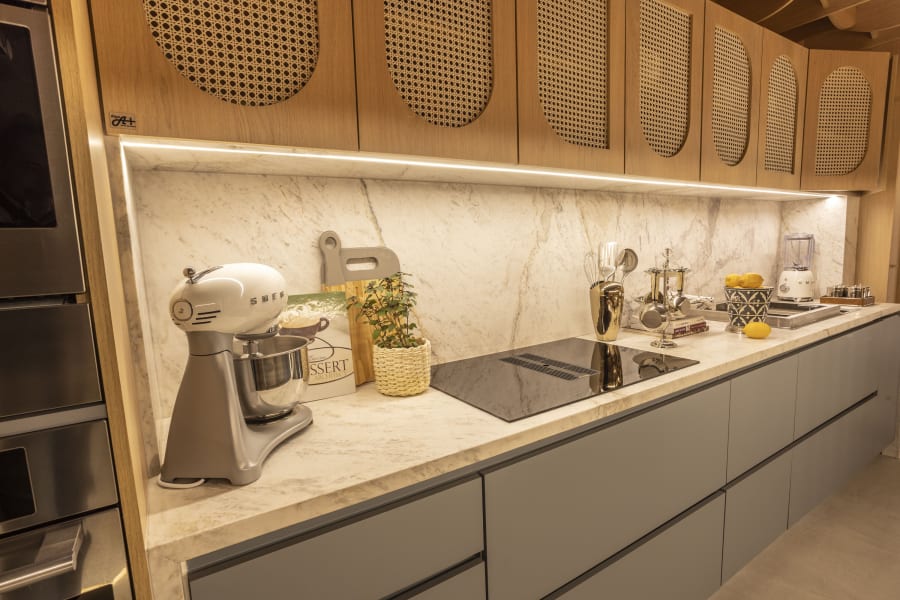 Sage grey galley kitchen with cane fronted oak cabinets and a white Smeg stand mixer