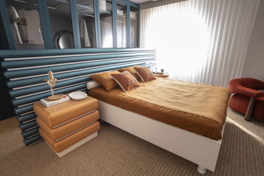 Bedroom at CASACOR Curitiba with teal leather bolster headboard and rust linen bedding