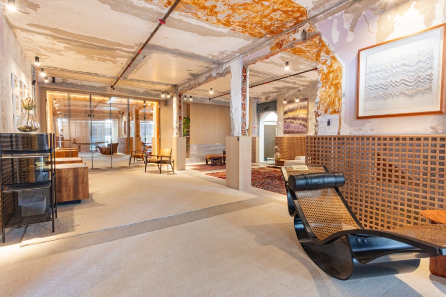 Raw plaster loft at CASACOR Minas with a black Rio chaise longue and wooden lattice wall