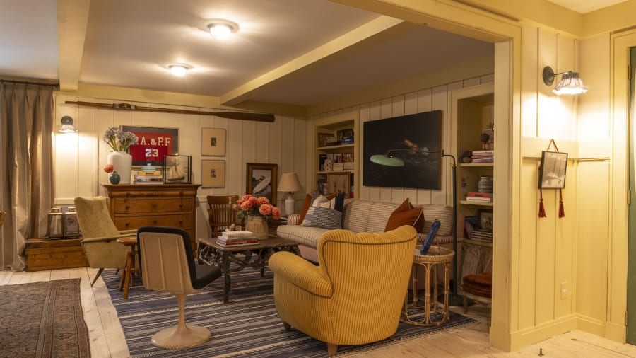 Family room at CASACOR São Paulo with yellow board walls, mustard armchair and striped rug