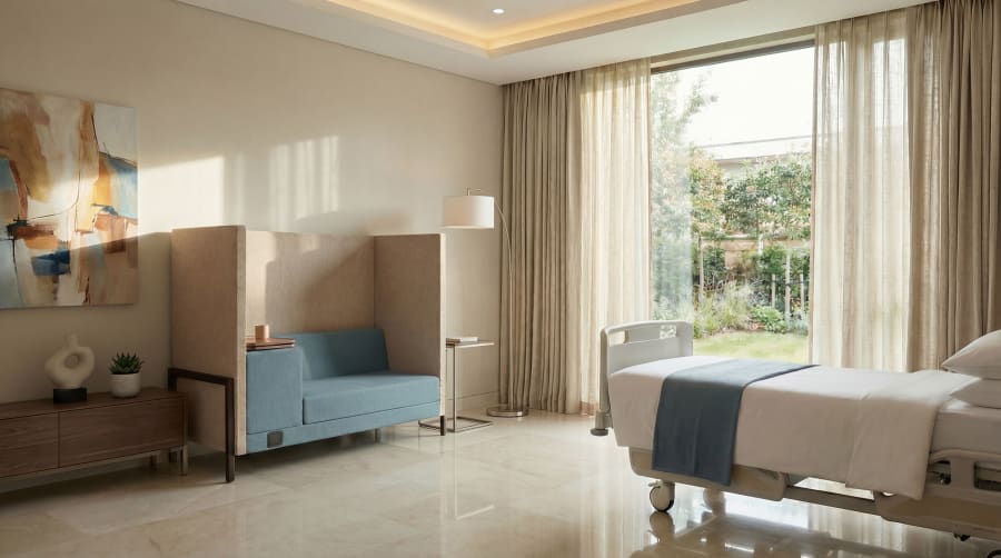 A hospital suite with a blue Cremme Sante companion sofa beside a patient bed and garden window