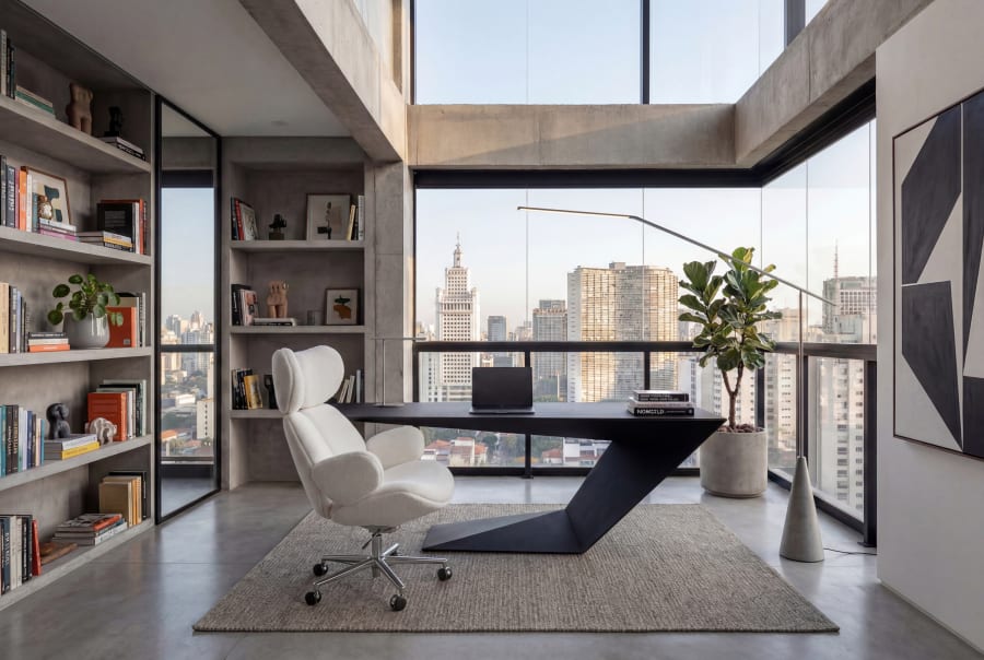 A sculptural black Roche Bobois desk and white boucle chair in a concrete loft above the city