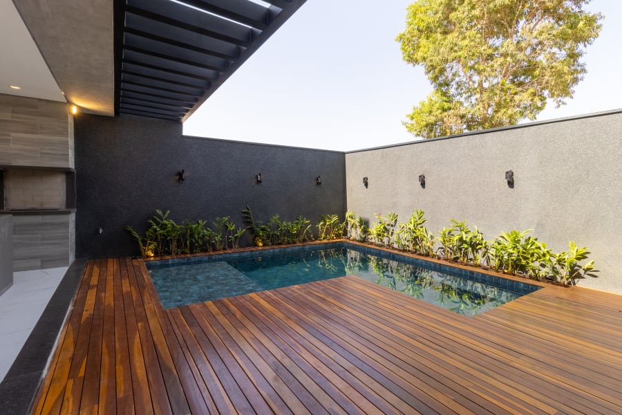 Courtyard plunge pool set in an ipê deck against dark stone walls and planting
