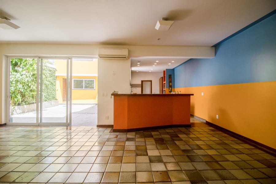 Empty kitchen with orange counter, blue and yellow painted walls and terracotta tile floor