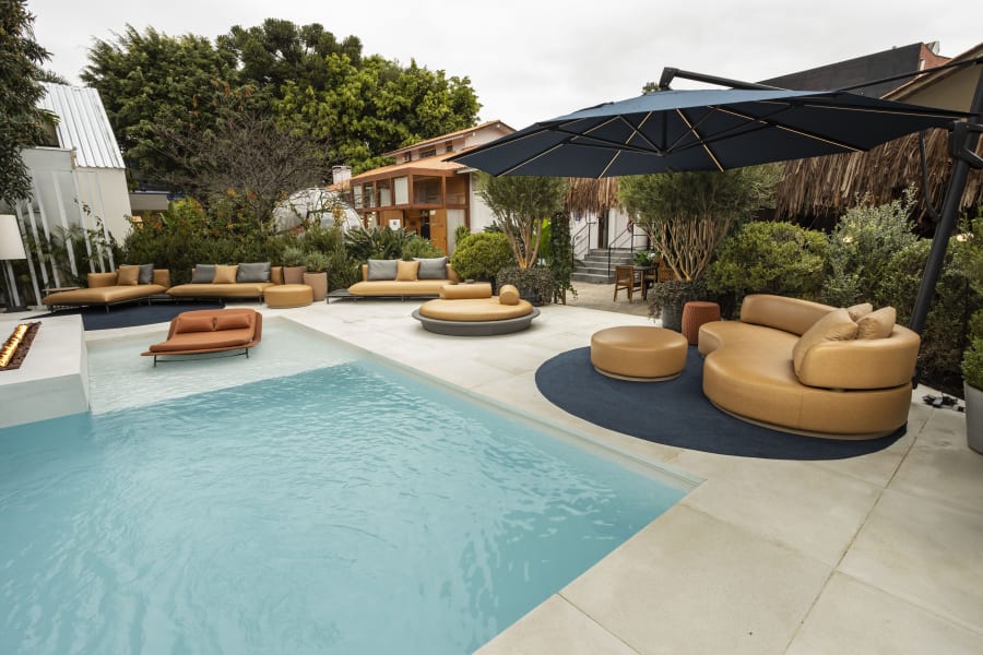 Pool with tan leather loungers and a cantilever parasol beside planted borders
