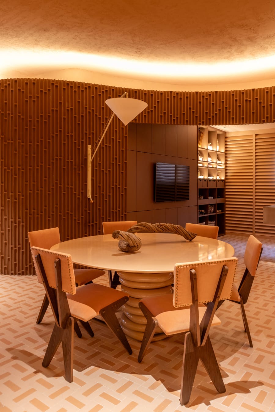 Round dining table with timber and leather chairs on a terracotta herringbone tile floor