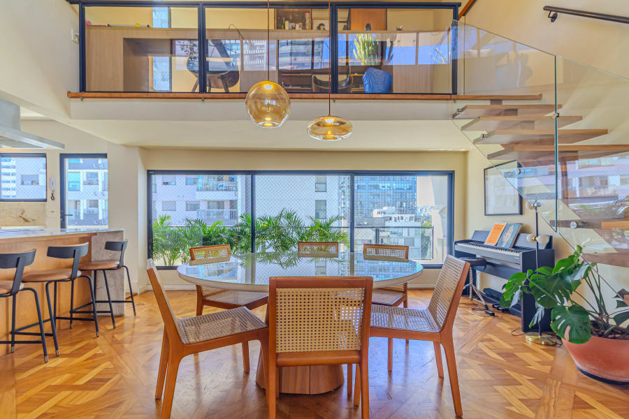 Duplex penthouse with round dining table, cane chairs and mezzanine over glass