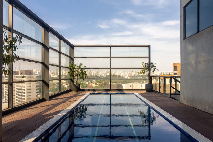 Rooftop lap pool inside a black steel and glass enclosure over São Paulo
