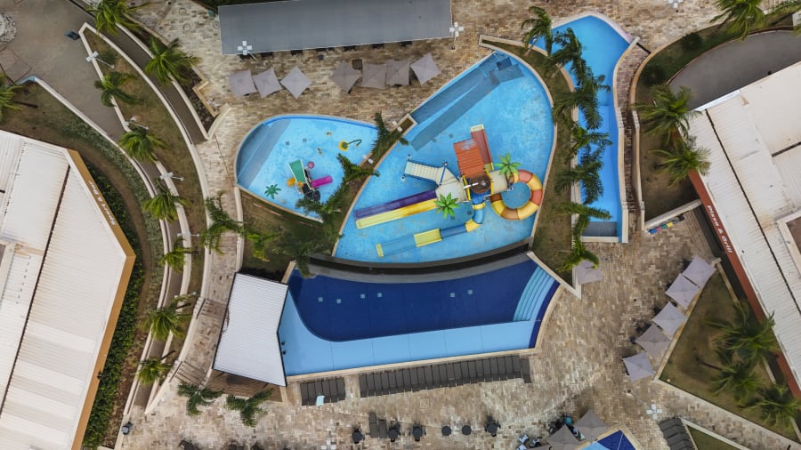Drone view straight down onto Enjoy Solar curved pools, water slide and palms