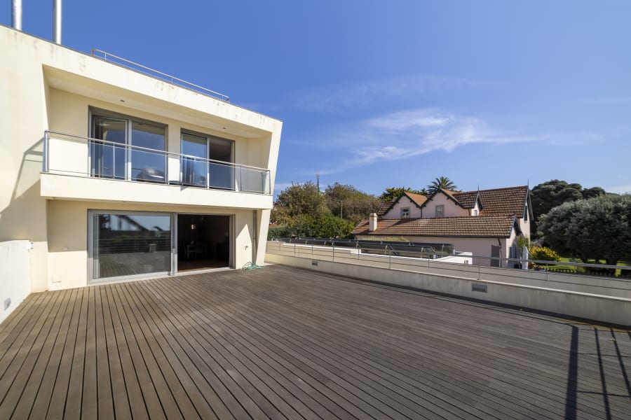 White villa with glass balconies above a wide timber roof deck in Gaia