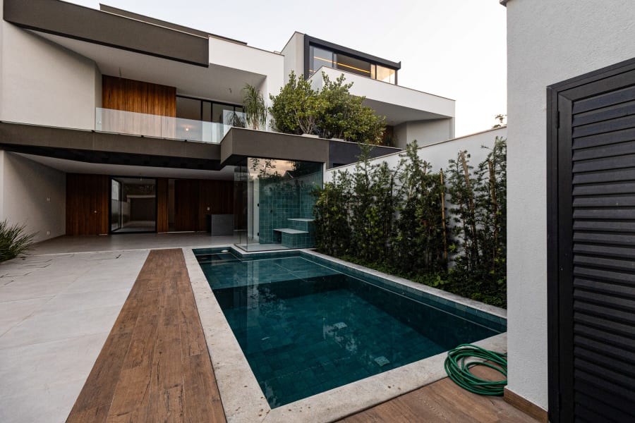 Modern new build with timber cladding and dark green pool beside a timber deck