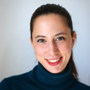 image Portätfoto von Katharina van Bronswijk. Sie trägt einen blauen Rollkragenpullover und hat ihre langen braunen Haare zu einem Pferdeschwanz gebunden.