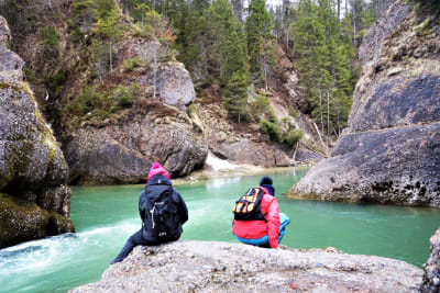 Zwei Frauen sitzen mit winterlicher Kleidung auf Felsen an einem See