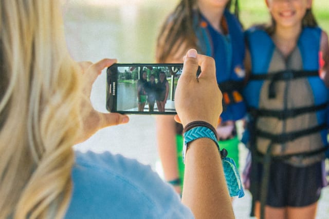 Girl takes photo of campers on a dock with her phone