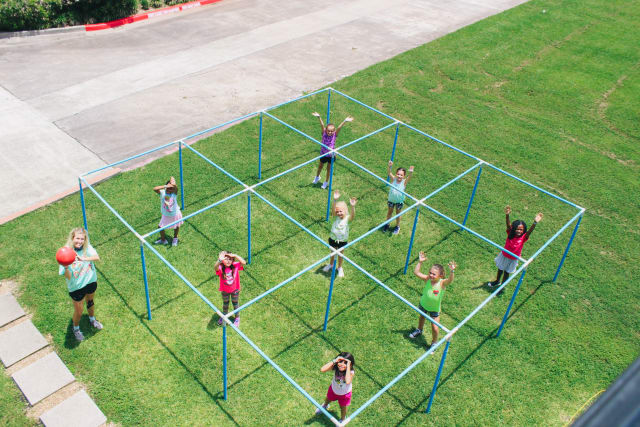 A drone shot of girls playing 9-square and their counselor holding the ball