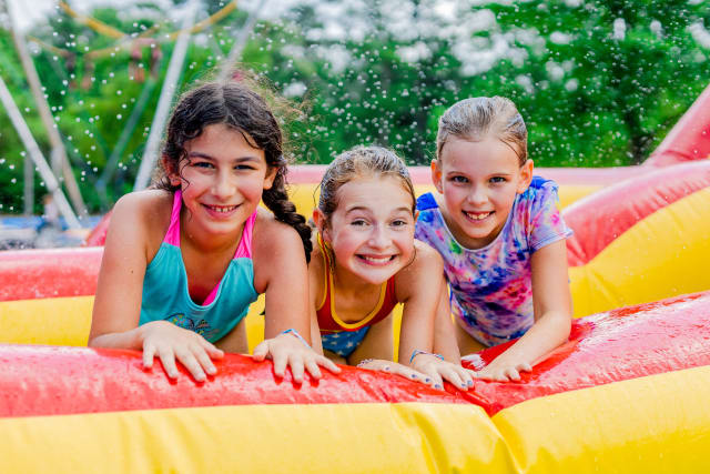 Three girls smile together on a water inflatable