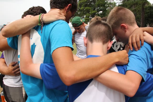 Young boy campers praying in a circle