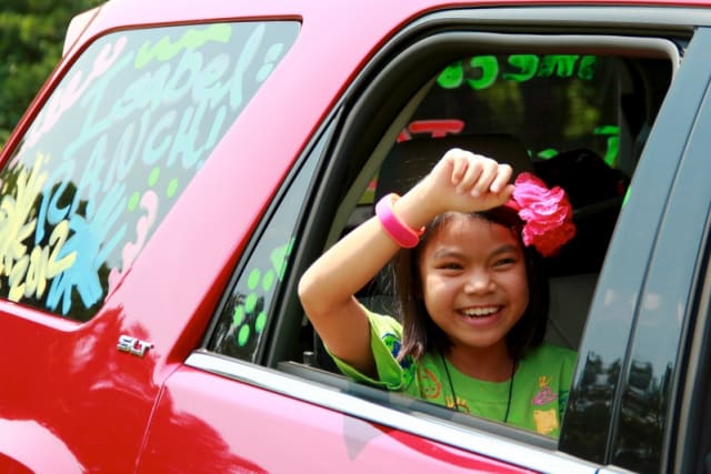 Young camper waving in the back seat