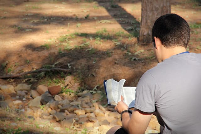 Guy Reading Bible At Camp