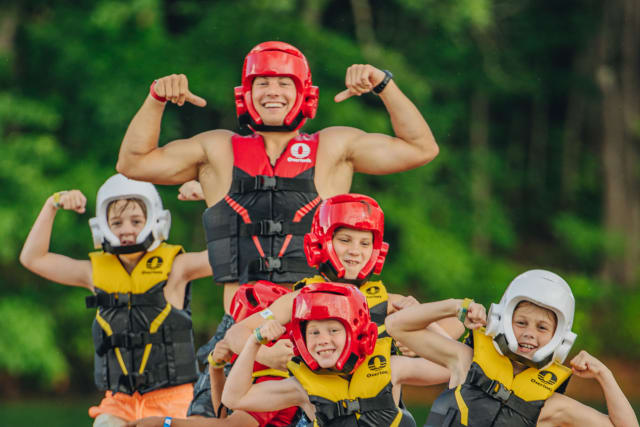 Camp counselor and campers posing on an inflatable banana boat on the lake
