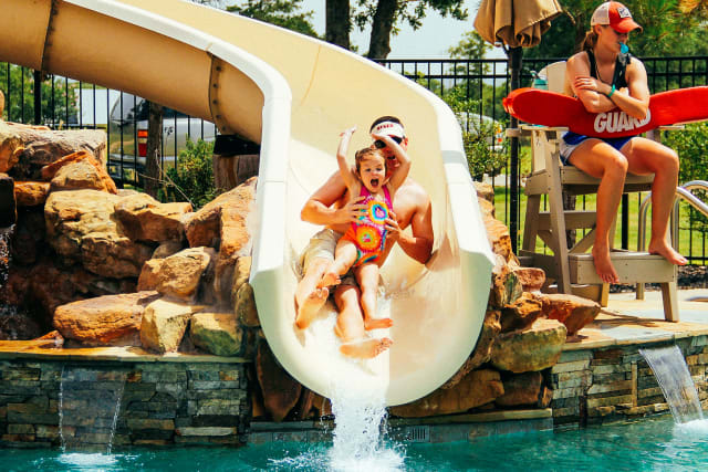 father and daughter on the water slide at the pool
