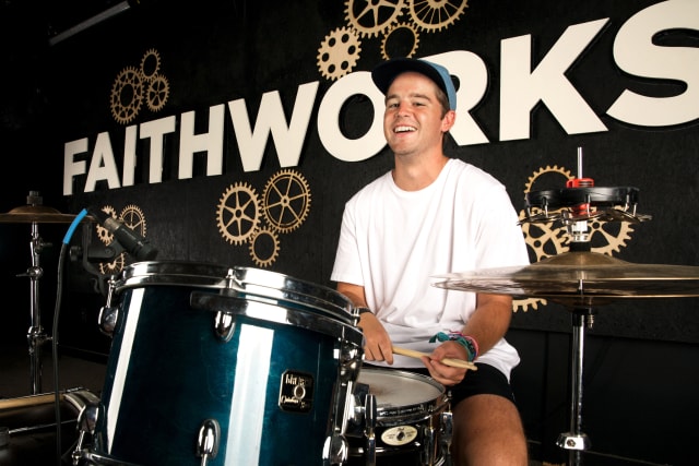 Drummer sits at a drum kit on stage