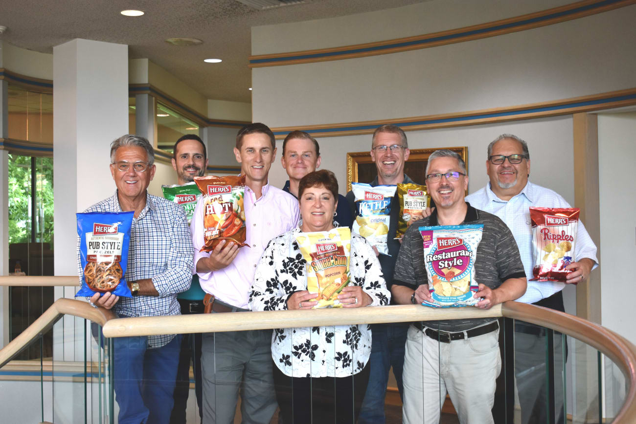 Herr Food’s executive team holding their favorite bag of Herr’s products.