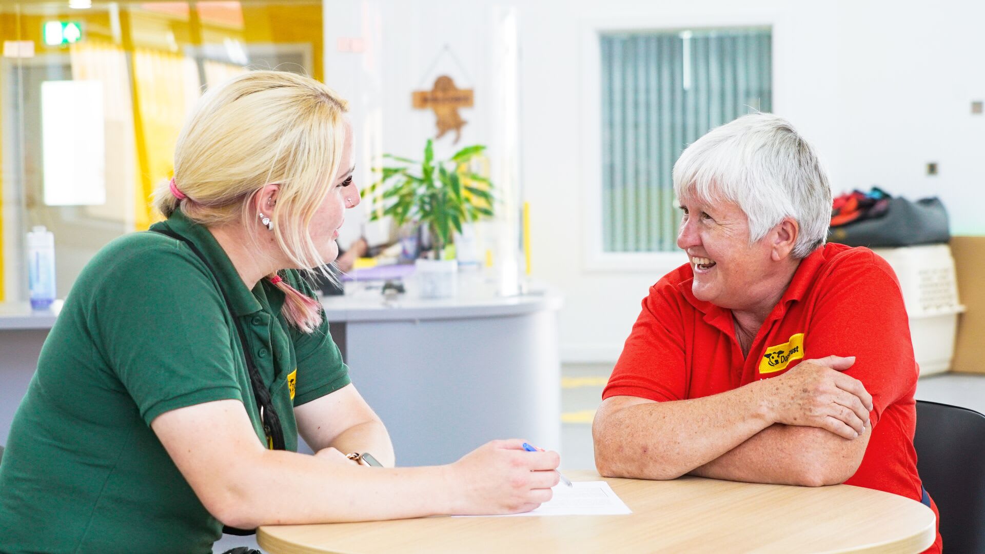 Volunteer with Canine Carer at a table