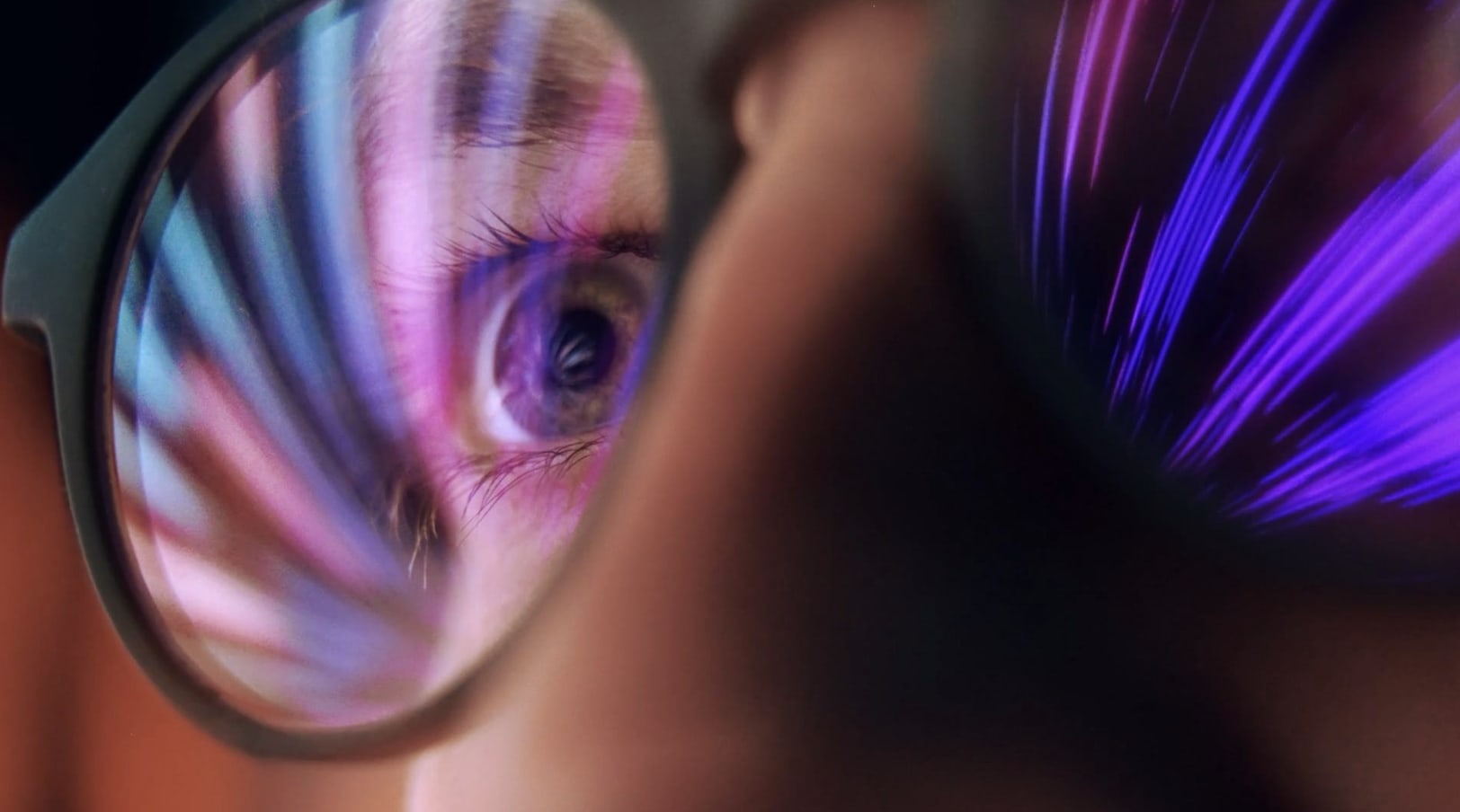 Person's face with glasses reflecting violet lights